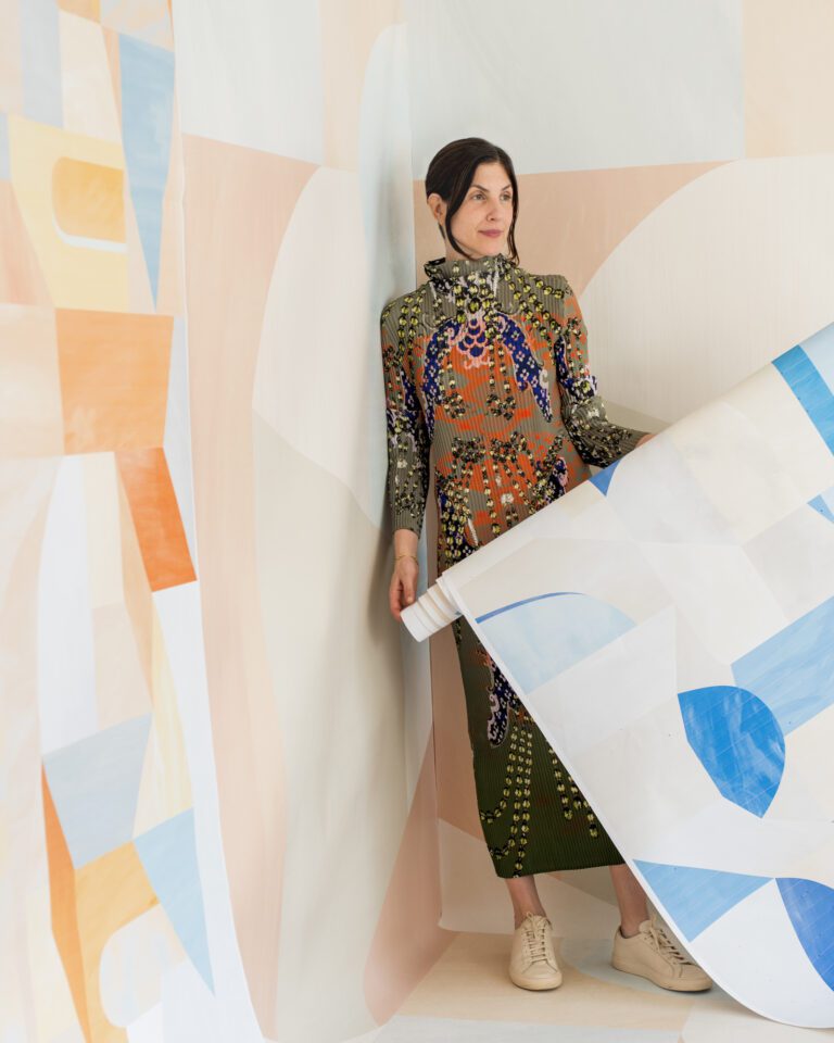 Woman standing with wallpaper installation, walls are pink and blue